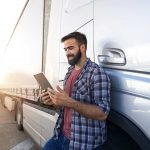 homme avec une tablette à côté d'une semi-remorque