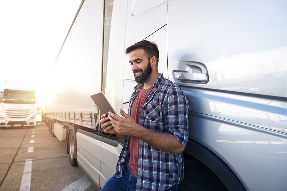 homme avec une tablette à côté d'une semi-remorque