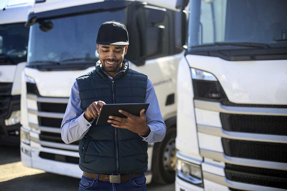 homme avec une tablette à côté d'une semi-remorque