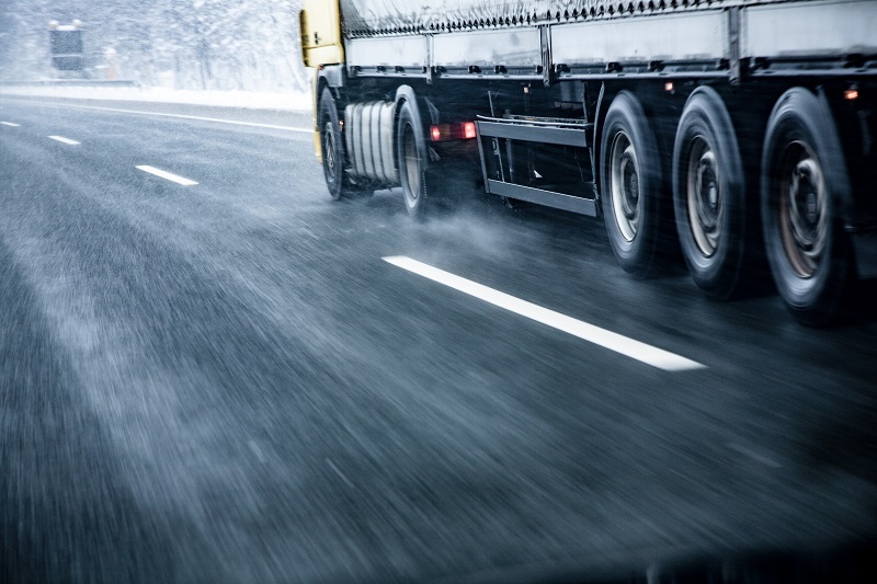 Camion roulant sur une route mouillée et glissante en hiver